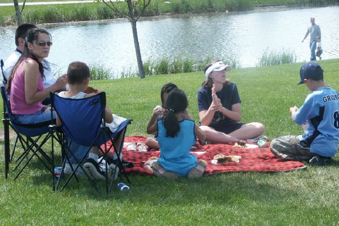 Students and their families gather water-side during a NBC picnic.