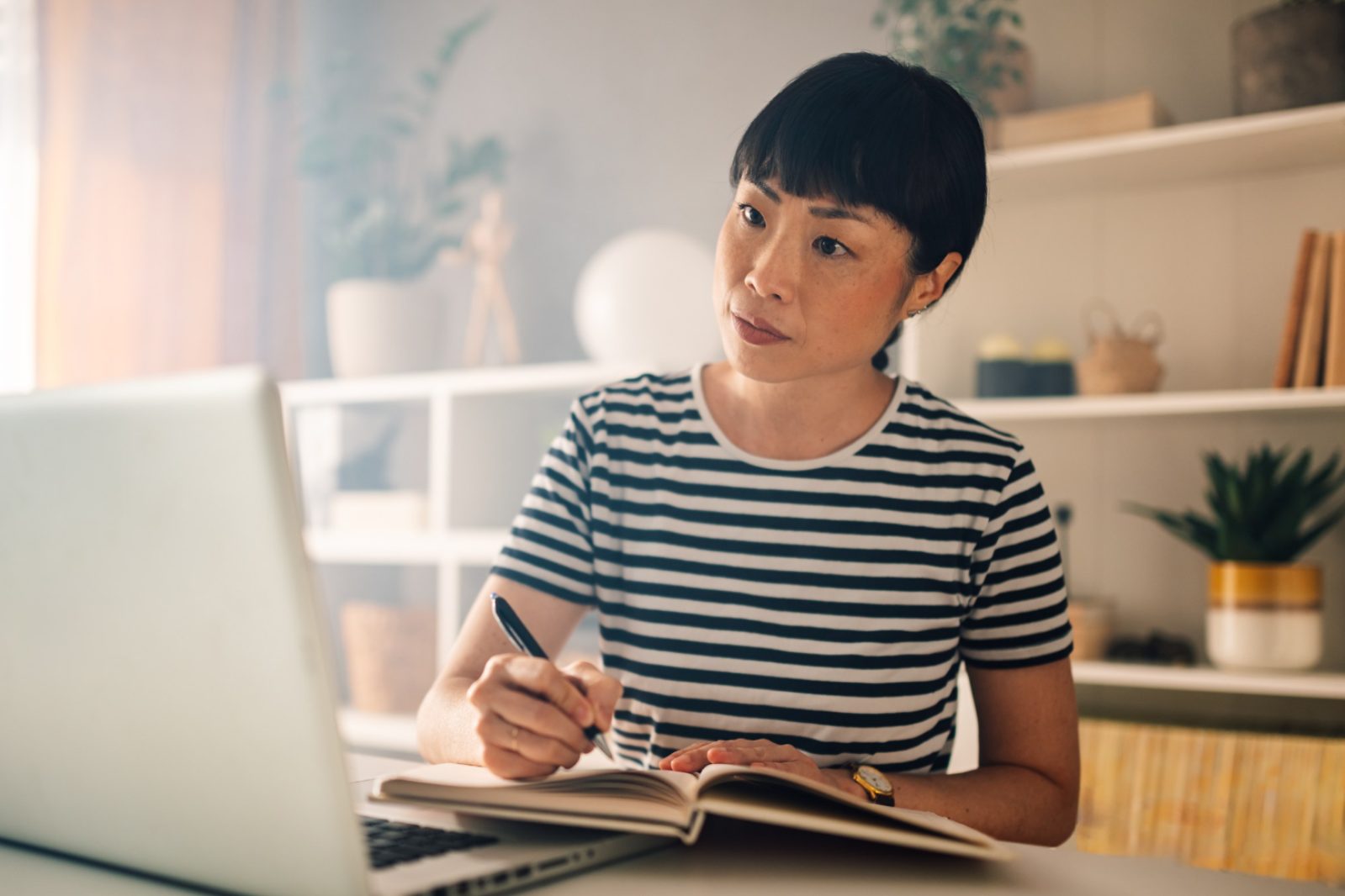 woman works with laptop and takes notes at home